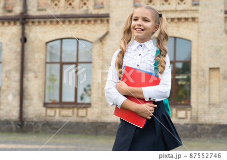 Happy school child in uniform back-to-school carrying books and backpack, copy space Happy school child in uniform back-to-school carrying books and backpack, copy space 87552746