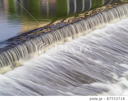 A small flat cascade in a calm river 87553718