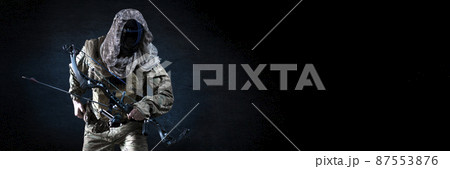 Unrecognizable silent killer with a compound bow in military uniform against a dark concrete wall. Concept of modern military special operations. Unrecognizable silent killer with a compound bow in military uniform against a dark concrete wall. Concept of modern military special operations. 87553876