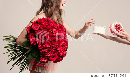 Beautiful lady with red roses taking a sweet from 87554291