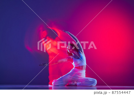 Young sportive beautiful girl, hip-hop dancer dancing hip hop isolated on purple background in pink neon light. Youth culture, style and fashion, action. 87554447