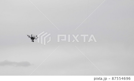 Flying helicopter dron on a background of white clouds 87554696