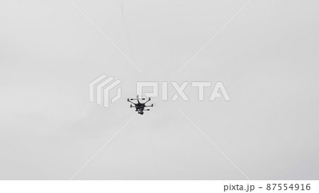 Flying helicopter dron on a background of white clouds Flying helicopter dron on a background of white clouds 87554916