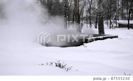 Pipe heating system with white steam out of the ground.ground winter season. 87555230