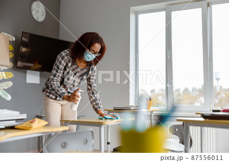 Teacher disinfecting tables in school during coronavirus epidemic 87556011