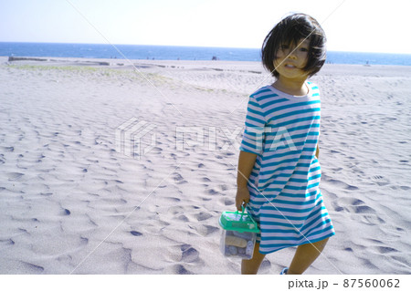 砂浜で貝拾いをする女の子 87560062