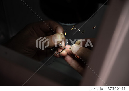 The technician solders the metal frame of the glasses. 87560141