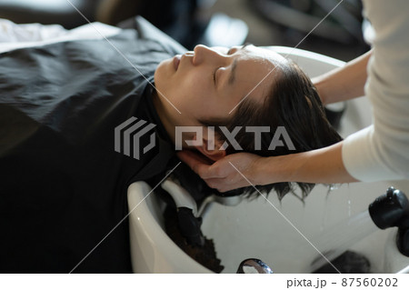 美容室でシャンプーしてもらう男性 87560202