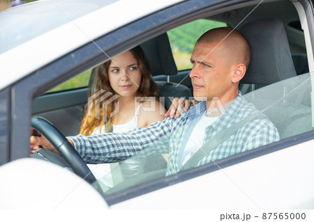 Focused man driving car with girl in passenger seat 87565000