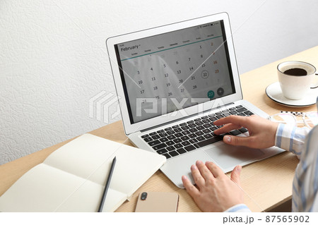 Woman using calendar app on laptop in office, closeup 87565902