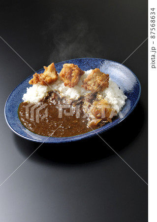 福神漬けも乗っている熱々唐揚げカレーを黒背景で撮影 福神漬けも乗っている熱々唐揚げカレーを黒背景で撮影 87568634
