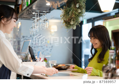 セルフサービスのカフェのカウンターでパスタを受け取る若い女性客 セルフサービスのカフェのカウンターでパスタを受け取る若い女性客 87569957