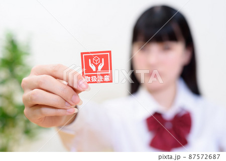 気難しい時期の女性　女子高校生　思春期　取扱注意のシールを持つ　 87572687