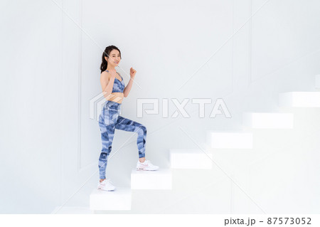 階段を上るスポーツウェアの若い女性 87573052