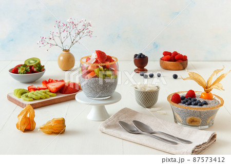 Low angle view of chia pudding dessert with summer berries, strawberries, kiwi and coconut slices, embellished with a mint sprig. No people. 87573412