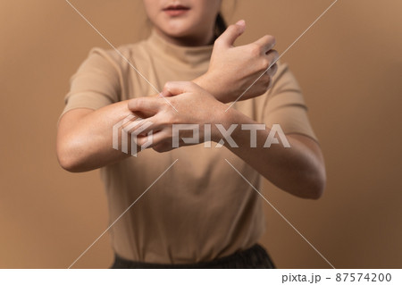 Asian woman was sick with irritate itching her skin standing isolated on beige background. Asian woman was sick with irritate itching her skin standing isolated on beige background. 87574200