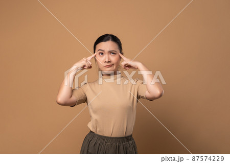 Asian woman feel confuse, standing isolated on beige background. 87574229
