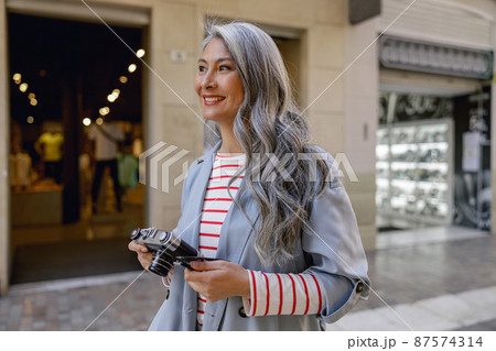 Busy mature lady taking stroll through city Busy mature lady taking stroll through city 87574314