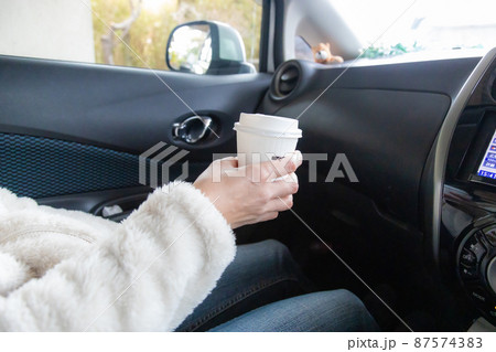 車内でコンビにコーヒーを飲む女性 87574383