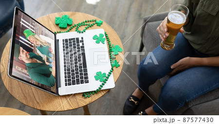 Caucasian woman holding beer at bar making st patrick's day video call to friends on laptop Caucasian woman holding beer at bar making st patrick's day video call to friends on laptop 87577430