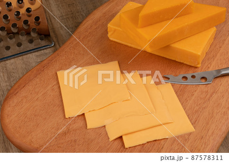 sliced cheddar cheese on the brown wood plate 87578311