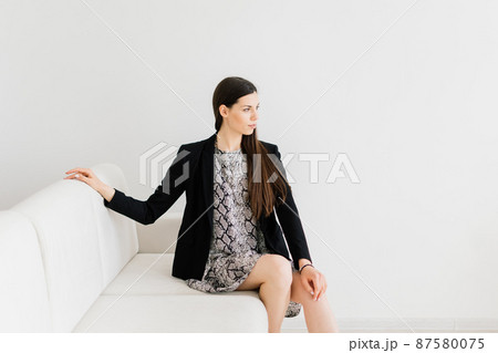 Cozy living room happy woman sitting on couch. European female enjoy lazy weekend or vacation 87580075