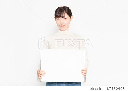 白い壁の前に立って大きなスケッチブックを見せる女性 87580403