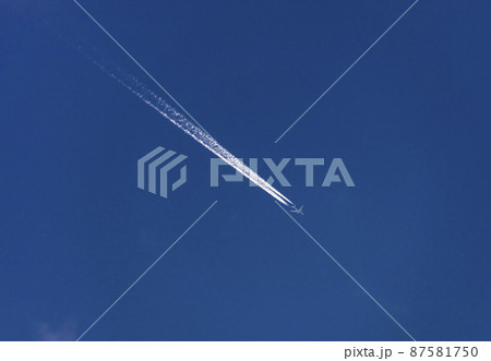 Route of an airplane with white contrail in the blue sky. 87581750