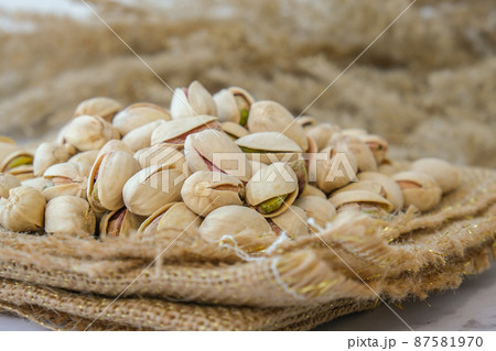 Pistachios in burlap sack on concrete table. Organic pistachios. Vegan Healthy food high protein. Dietary nutrition. Concept of nuts Pistachios in burlap sack on concrete table. Organic pistachios. Vegan Healthy food high protein. Dietary nutrition. Concept of nuts 87581970