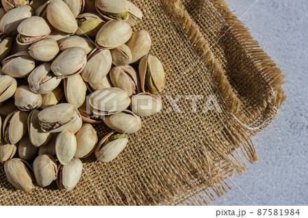 Pistachios in burlap sack on concrete table. Organic pistachios. Vegan Healthy food high protein. Dietary nutrition. Concept of nuts 87581984