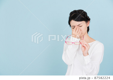 目をおさえる白いブラウスを着た女性 目をおさえる白いブラウスを着た女性 87582224