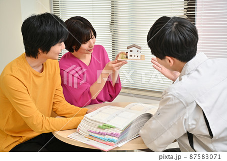 工務店の事務所で建築図面を見ながら打ち合わせをする夫婦と社員 工務店の事務所で建築図面を見ながら打ち合わせをする夫婦と社員 87583071