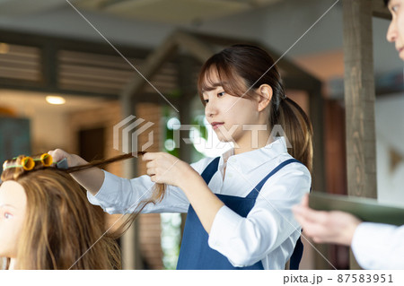 パーマの練習をする若いスタッフ 87583951