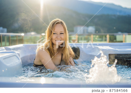 Portrait of young carefree happy smiling woman relaxing at hot tub during enjoying happy traveling moment vacation life against the background of green big mountains 87584566