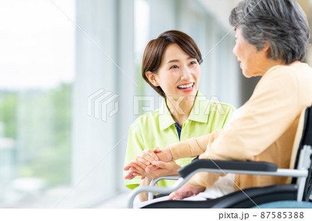 車椅子のシニアの女性とミドルの介護福祉士 87585388