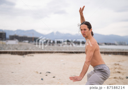 Caucasian man with long hair practicing qigong outdoors. Caucasian man with long hair practicing qigong outdoors. 87586214