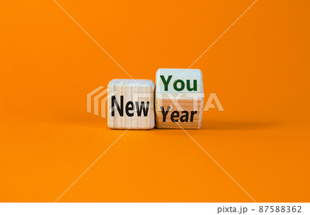 New year time. Turned a cube and changed the words 'new year' to 'new you'. Beautiful orange background. Copy space. Business and new year concept. New year time. Turned a cube and changed the words 'new year' to 'new you'. Beautiful orange background. Copy space. Business and new year concept. 87588362