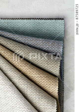 Fabric swatches in different colors are stacked for selection. A variety of shades of upholstery material for furniture and interior. Fabric texture close up. A set of multi-colored rolls of material Fabric swatches in different colors are stacked for selection. A variety of shades of upholstery material for furniture and interior. Fabric texture close up. A set of multi-colored rolls of material 87589725