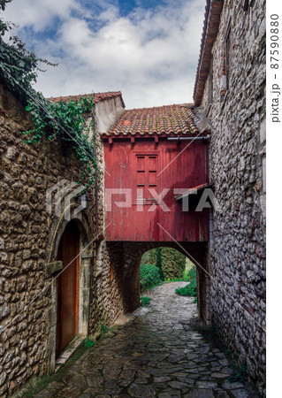 Stone arch cobblestone pavement interconnecting houses on alley without crowd. Stone arch cobblestone pavement interconnecting houses on alley without crowd. 87590880