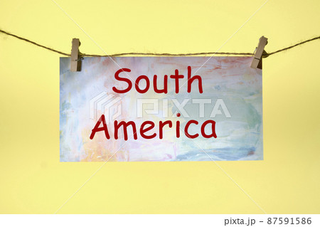 South America text written on paper suspended from a rope on a yellow background South America text written on paper suspended from a rope on a yellow background 87591586
