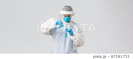 Covid-19, medical research, healthcare workers and quarantine concept. Tech lab doctor in clinic working on coronavirus vaccine, pouring liquid in another test-tube, wear personal protective costume Covid-19, medical research, healthcare workers and quarantine concept. Tech lab doctor in clinic working on coronavirus vaccine, pouring liquid in another test-tube, wear personal protective costume 87591755