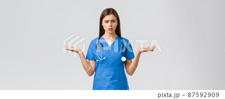Healthcare workers, prevent virus, insurance and medicine concept. Confused and puzzled female nurse, doctor in blue scrubs, spread hands sideways and shrugging, cant understand Healthcare workers, prevent virus, insurance and medicine concept. Confused and puzzled female nurse, doctor in blue scrubs, spread hands sideways and shrugging, cant understand 87592909