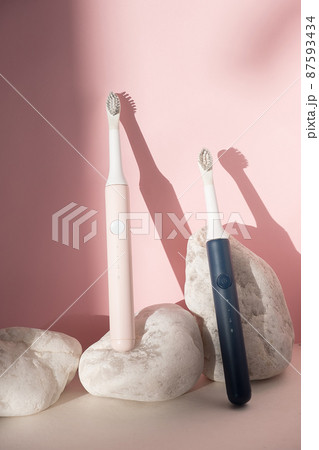 New modern ultrasonic toothbrushes. Dental care supplies with white stones on pink pastel background. Oral hygiene, dental health, healthy teeth. Dental products Ultrasonic vibration toothbrush. 87593434