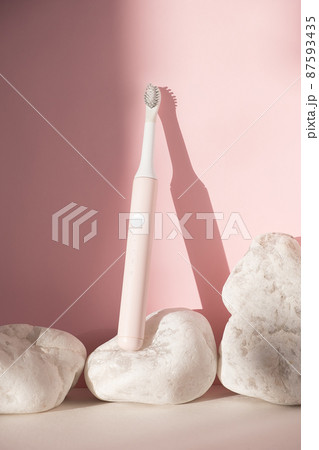 New modern ultrasonic toothbrush. Dental care supplies with white stones on pink pastel background. Oral hygiene, dental and gum health, healthy teeth. Dental products Ultrasonic vibration toothbrush. New modern ultrasonic toothbrush. Dental care supplies with white stones on pink pastel background. Oral hygiene, dental and gum health, healthy teeth. Dental products Ultrasonic vibration toothbrush. 87593435