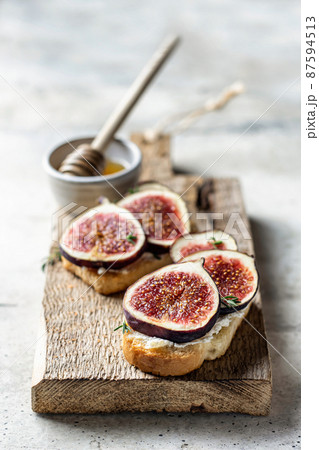 Two sandwiches with figs, thyme on a wooden board on textured background Two sandwiches with figs, thyme on a wooden board on textured background 87594513