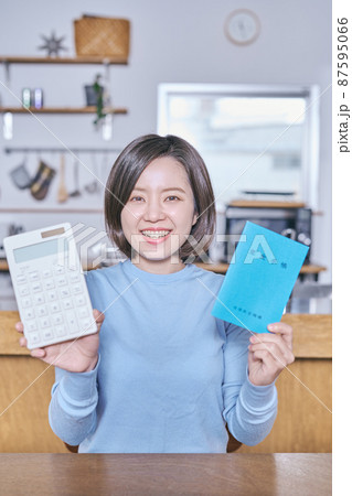 電卓と年金手帳を持つカメラ目線の若い女性 電卓と年金手帳を持つカメラ目線の若い女性 87595066