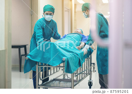 Doctor Getting their patient ready for the next procedure In the corridor, a medical team is pushing an emergency stretcher bed. Doctor Getting their patient ready for the next procedure In the corridor, a medical team is pushing an emergency stretcher bed. 87595201