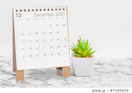 December 2022 desk calendar with plant on marble table. 87595656
