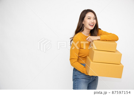 Happy Asian woman smiling and holding package parcel box isolated on white background, Delivery courier and shipping service concept 87597154