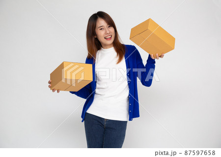 Happy Asian teenager woman smiling and holding package parcel box isolated on white background, Delivery courier and shipping service concept 87597658